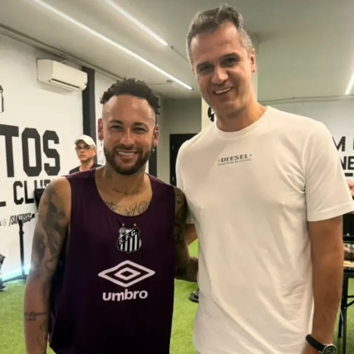 Thiago Taveira ao lado de um jogador profissional, num centro de treinamento