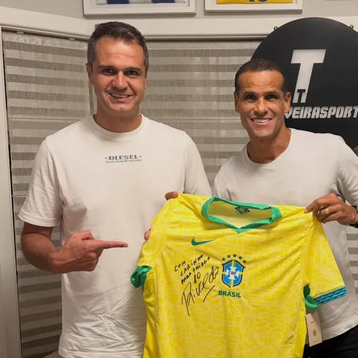 Thiago Taveira ao lado de um jogador que segura uma camisa da Seleção